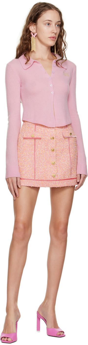 Model wears soft pink button-up sweater and pink plaid mini skirt designed by Sultry Virgin