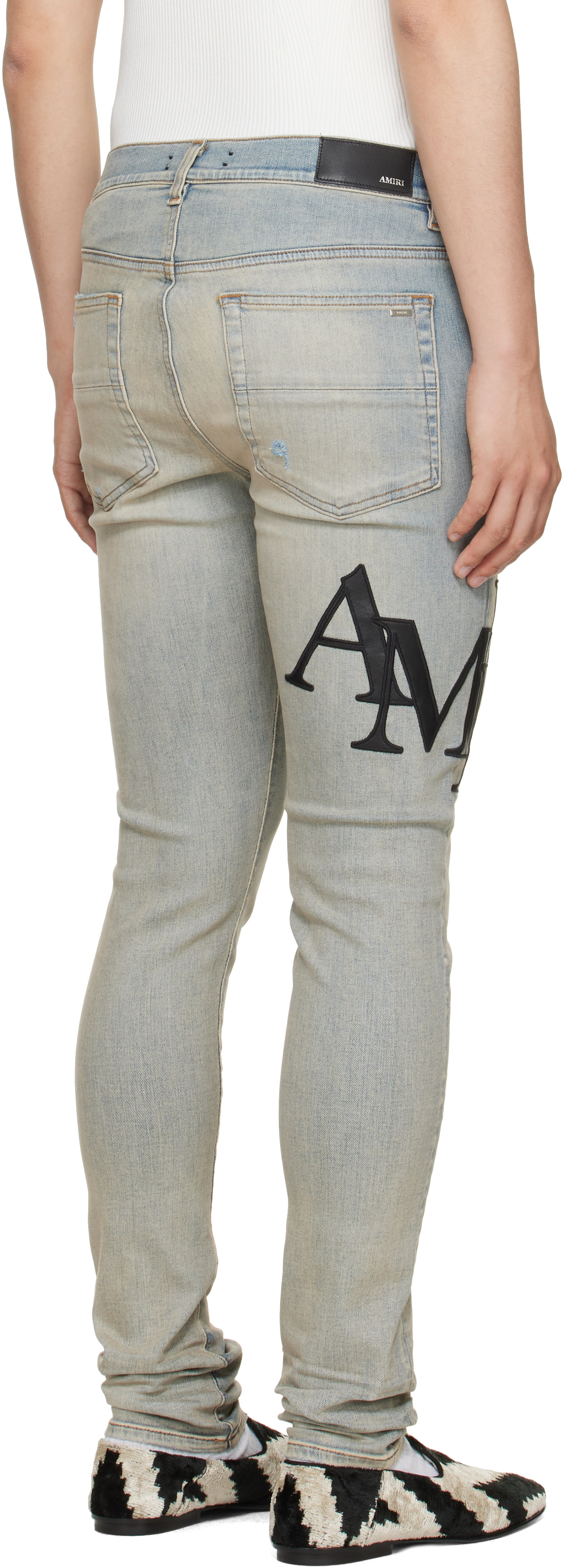 AMIRI: Blue Staggered Logo Skinny Jeans | SSENSE